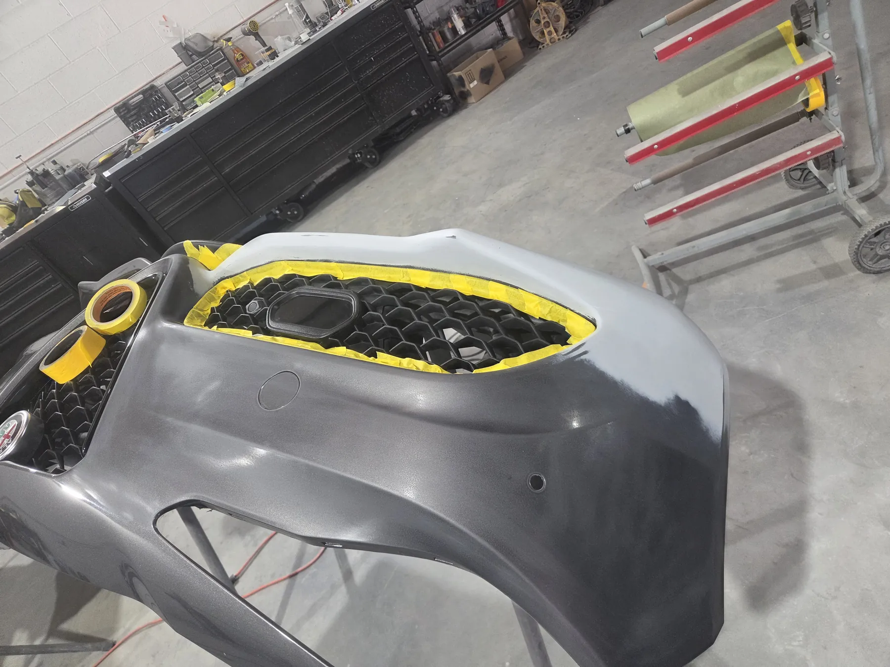 Gray Alfa Romeo bumper removed for preparation inside the Mastercraft Auto shop