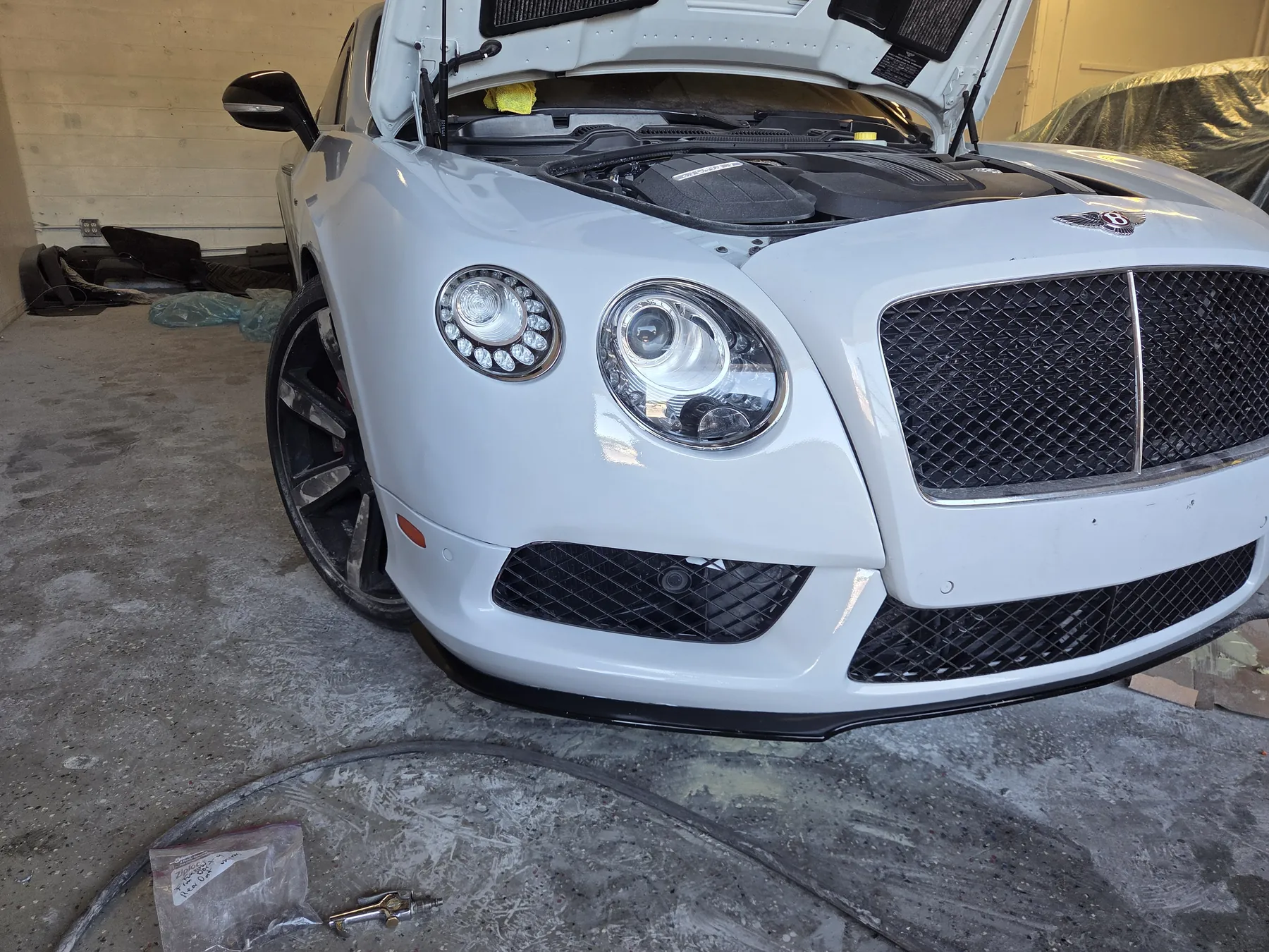 White Bentley front bumper after repair, refinishing, and reassembly