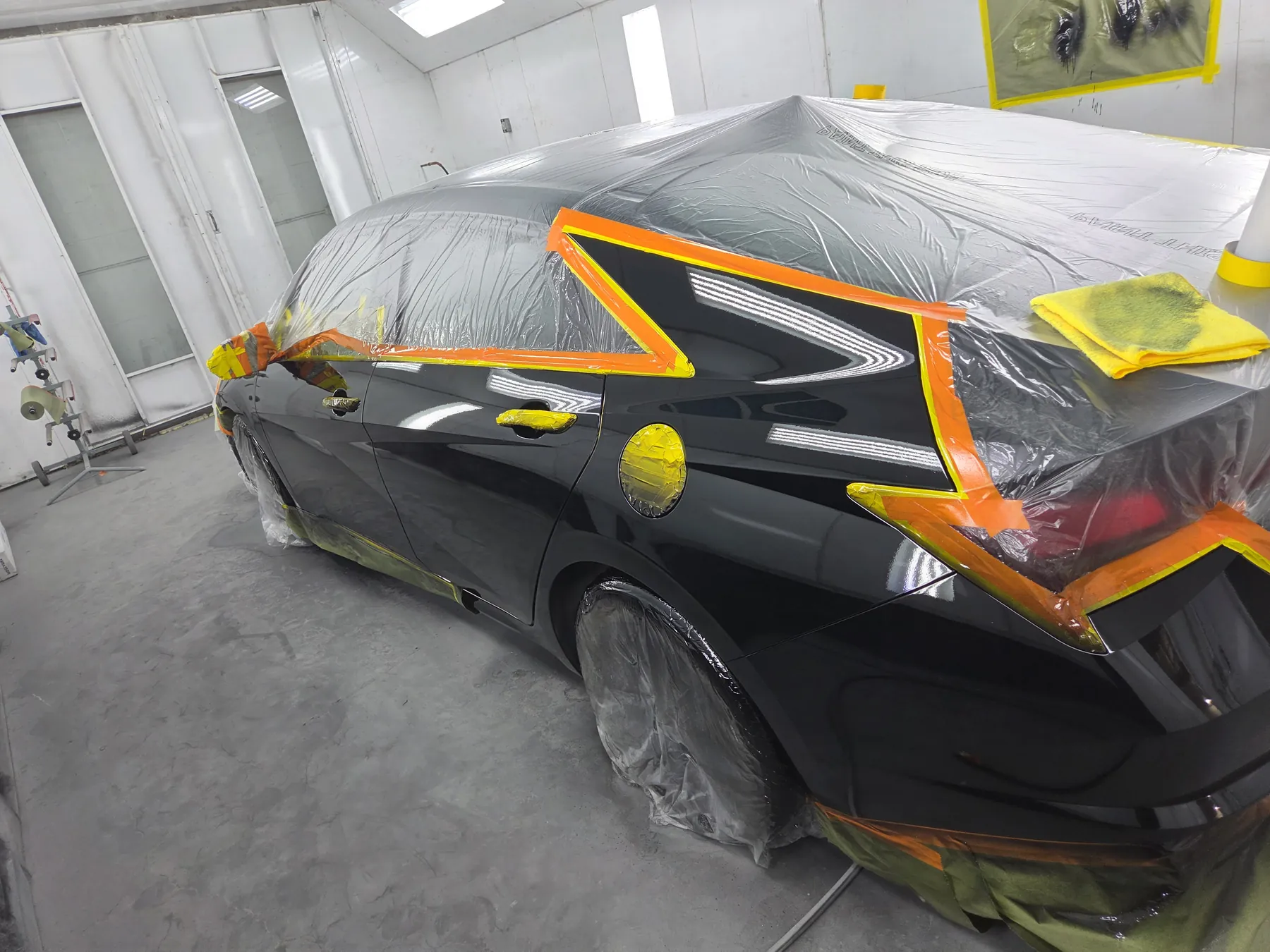 Black Cadillac masked in the paint booth during refinishing