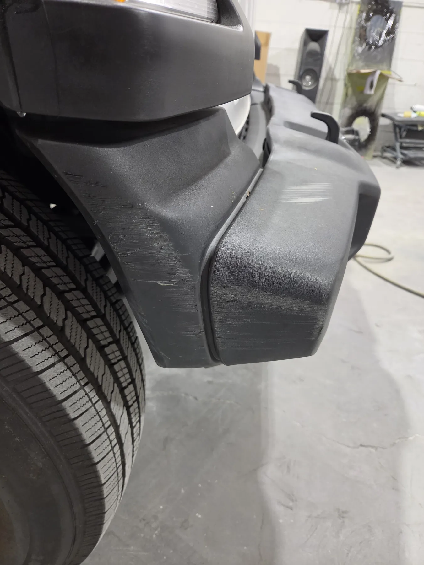 Black textured Jeep rear bumper with scrapes before repair