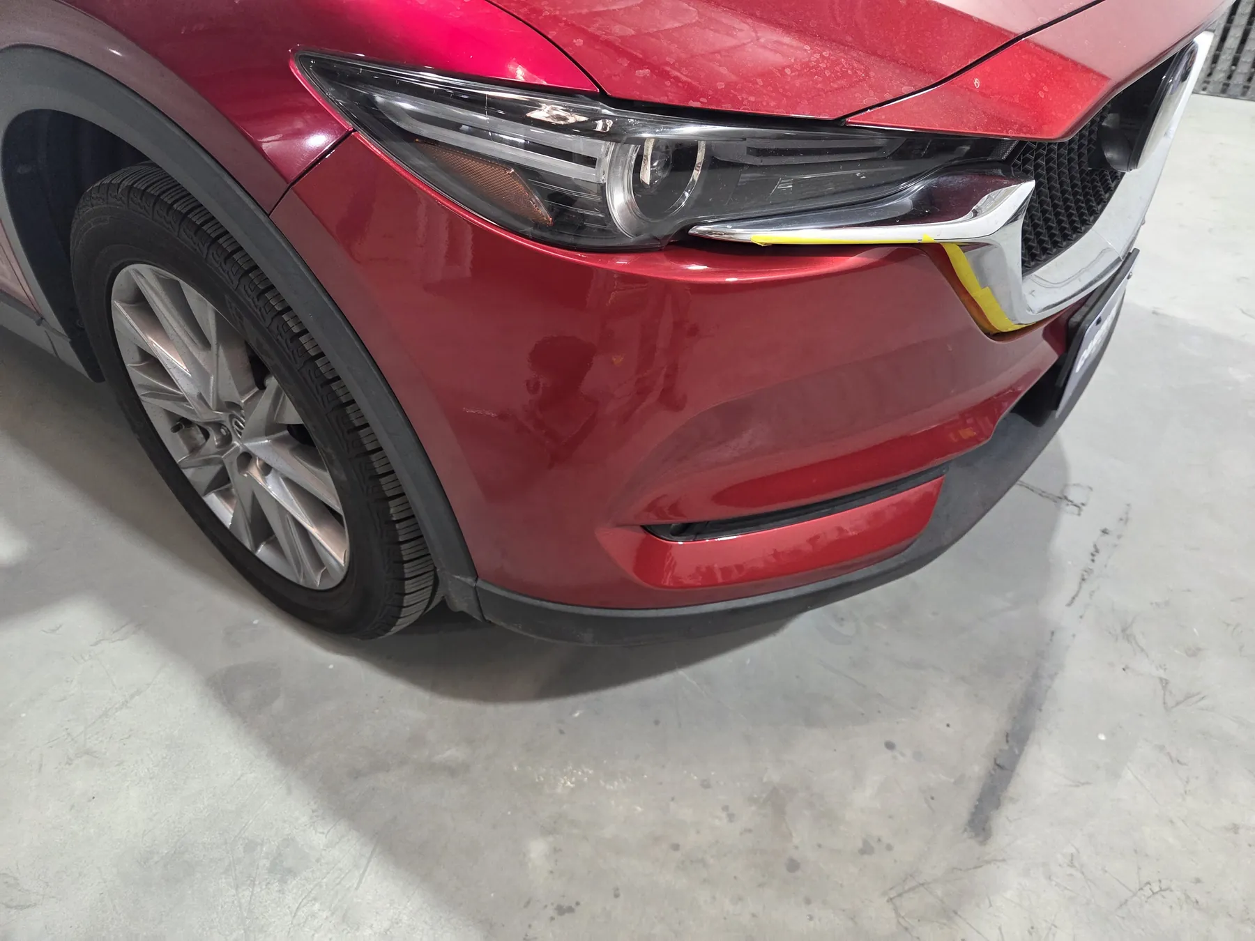 Red Mazda front bumper after repair and color-matched refinishing